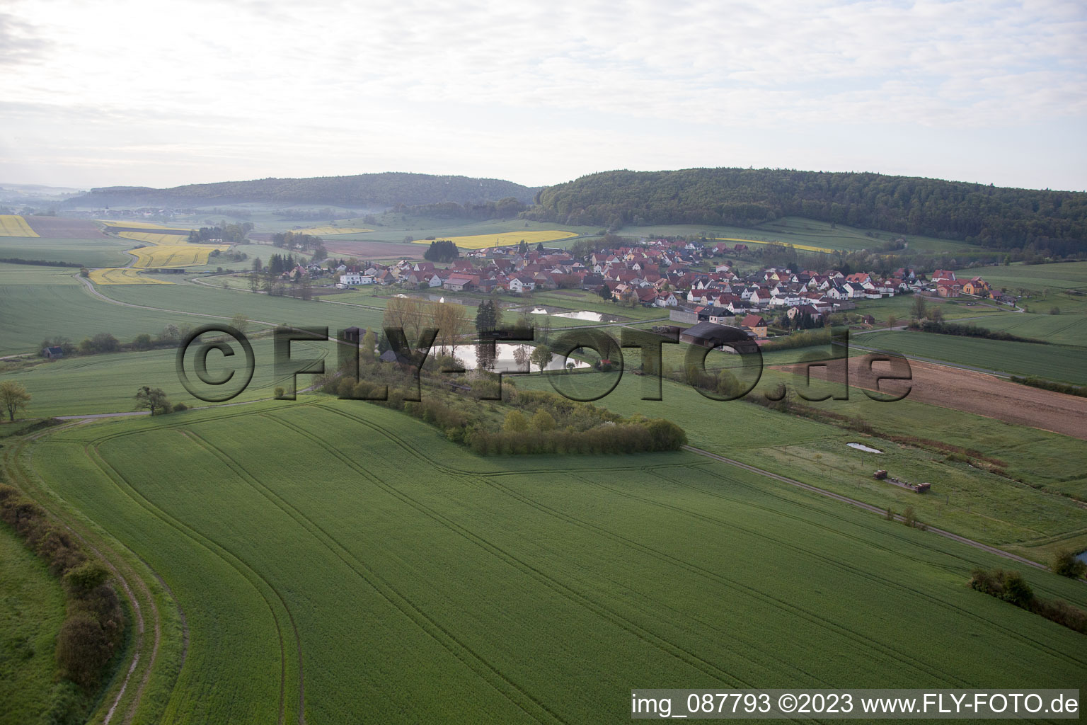 Dorf - Ansicht am Rande von landwirtschaftlichen Feldern und Nutzflächen in Geusfeld bei Rauhenebrach im Bundesland Bayern, Deutschland