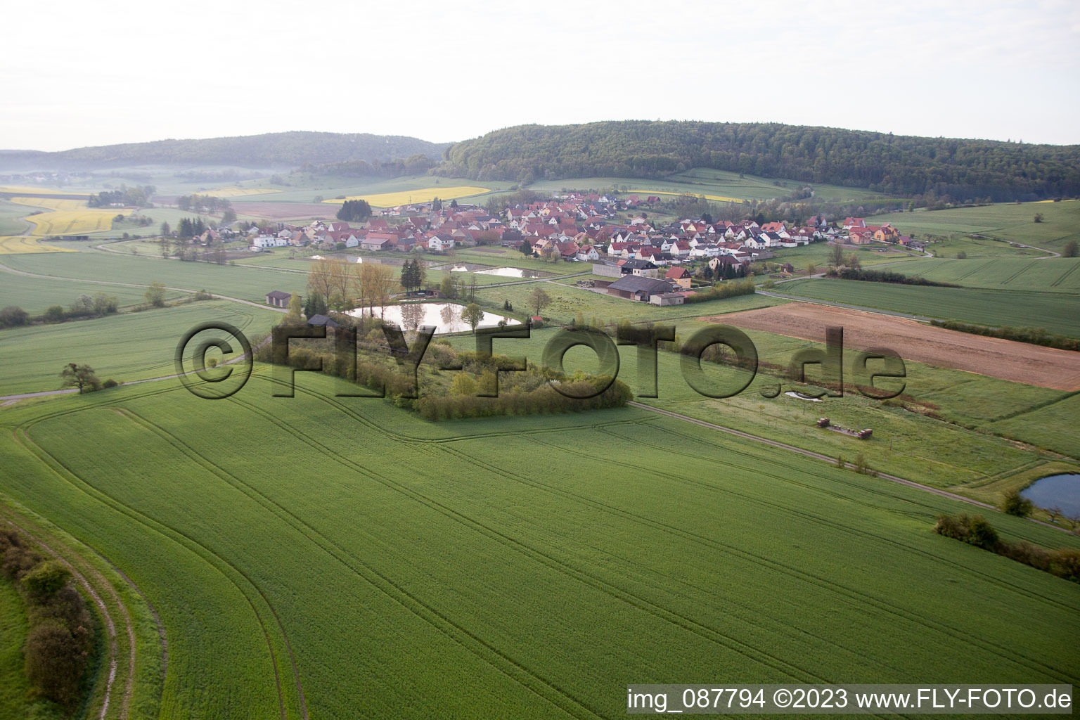 Luftbild von Dorf - Ansicht am Rande von landwirtschaftlichen Feldern und Nutzflächen in Geusfeld bei Rauhenebrach im Bundesland Bayern, Deutschland