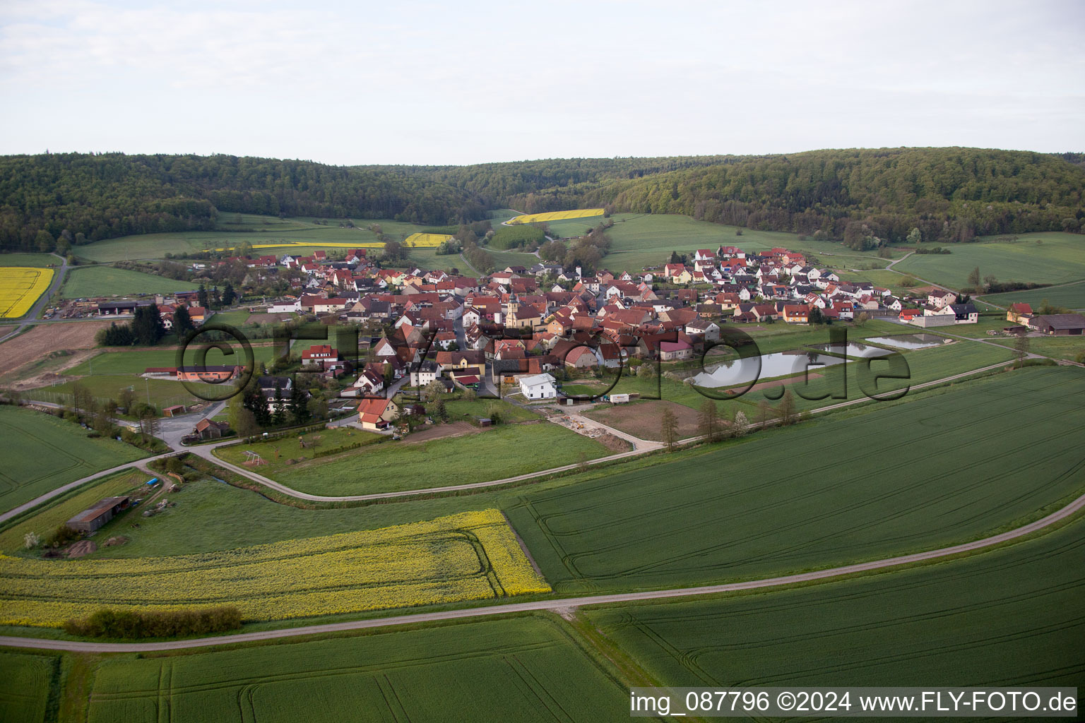 Schrägluftbild von Dorf - Ansicht am Rande von landwirtschaftlichen Feldern und Nutzflächen in Geusfeld bei Rauhenebrach im Bundesland Bayern, Deutschland