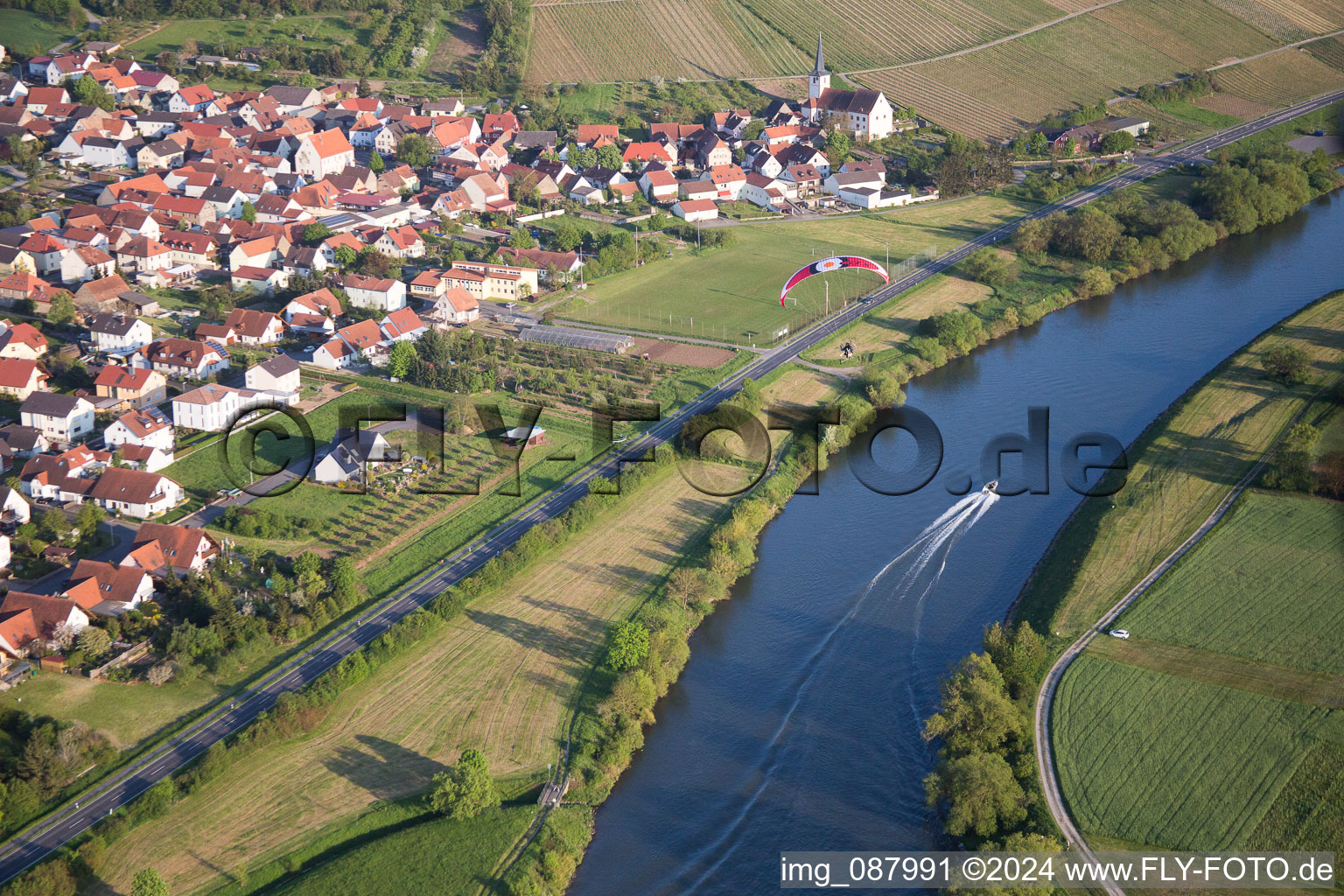 Dorfkern an den Fluß- Uferbereichen des Main mit Sportboot und Gleitschirm in Kolitzheim im Ortsteil Stammheim im Bundesland Bayern, Deutschland