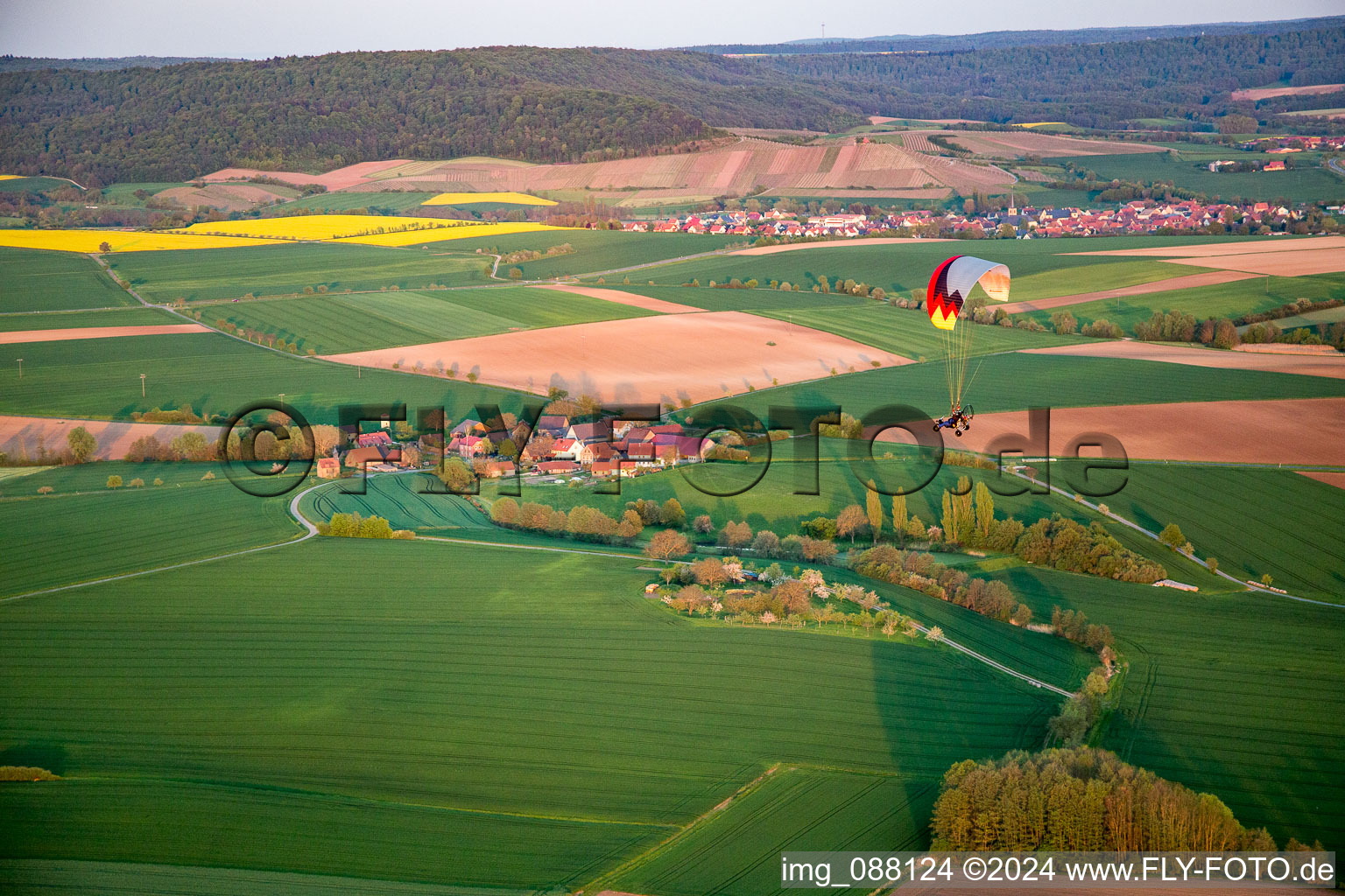 Gleitschirm über dem Ort im Ortsteil Wiebelsberg in Oberschwarzach im Bundesland Bayern, Deutschland