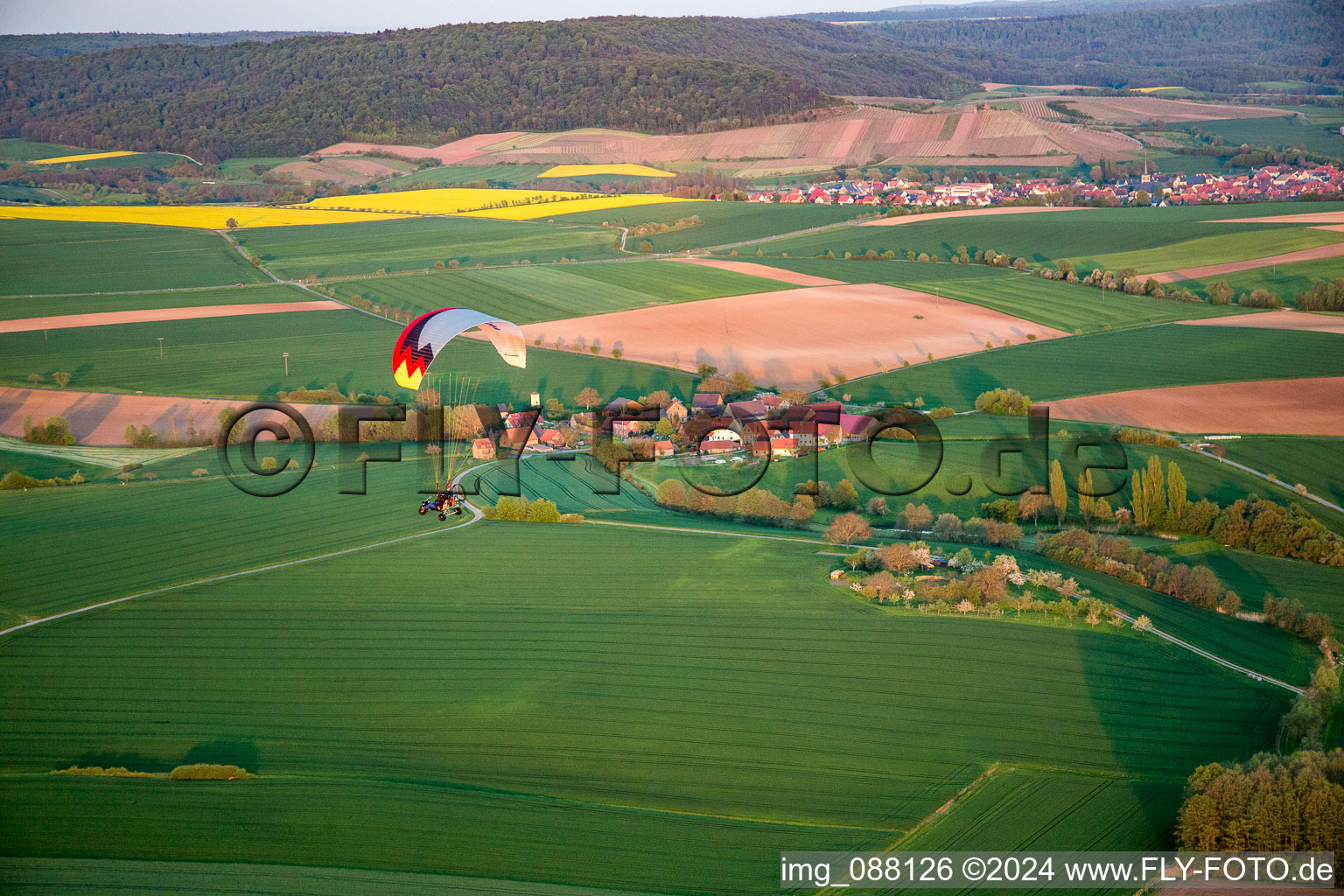 Luftaufnahme von Gleitschirm über dem Ort im Ortsteil Wiebelsberg in Oberschwarzach im Bundesland Bayern, Deutschland