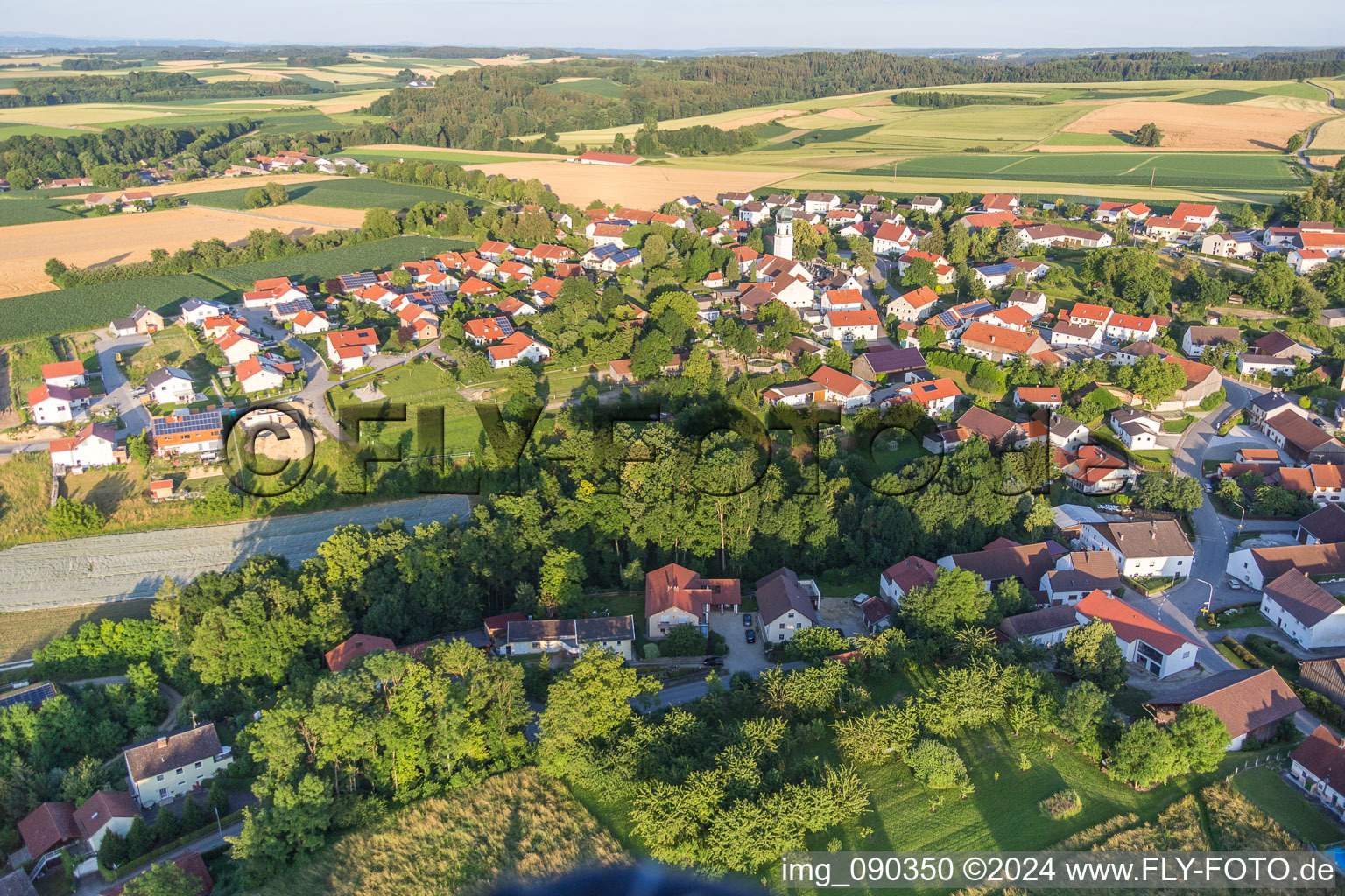 Dorf - Ansicht am Rande von landwirtschaftlichen Feldern und Nutzflächen in Zeholfing im Bundesland Bayern, Deutschland