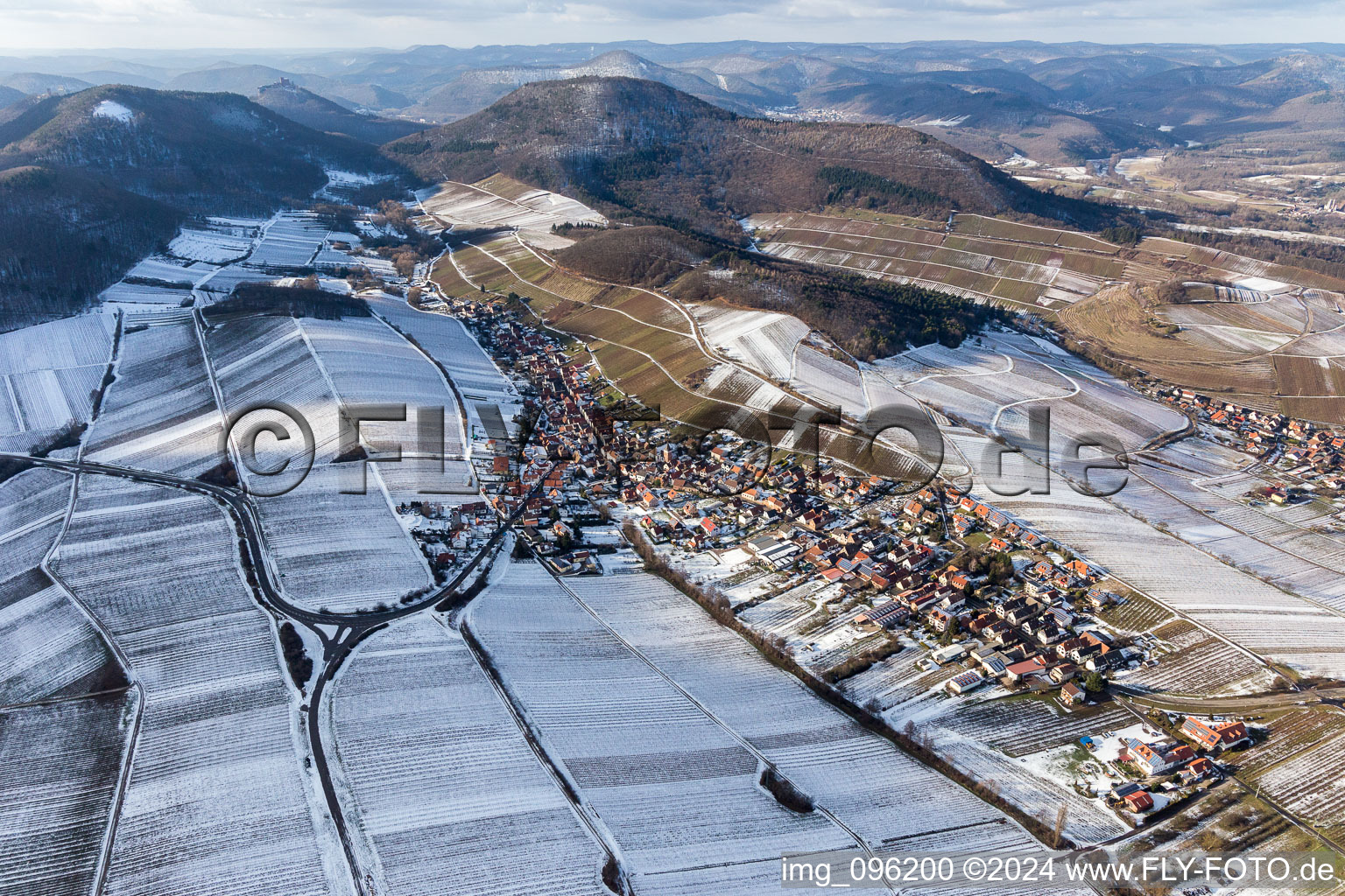 Winterlich schneebedeckte Dorf - Ansicht am Rande von beschneiten Weinbergen in Ranschbach im Bundesland Rheinland-Pfalz, Deutschland