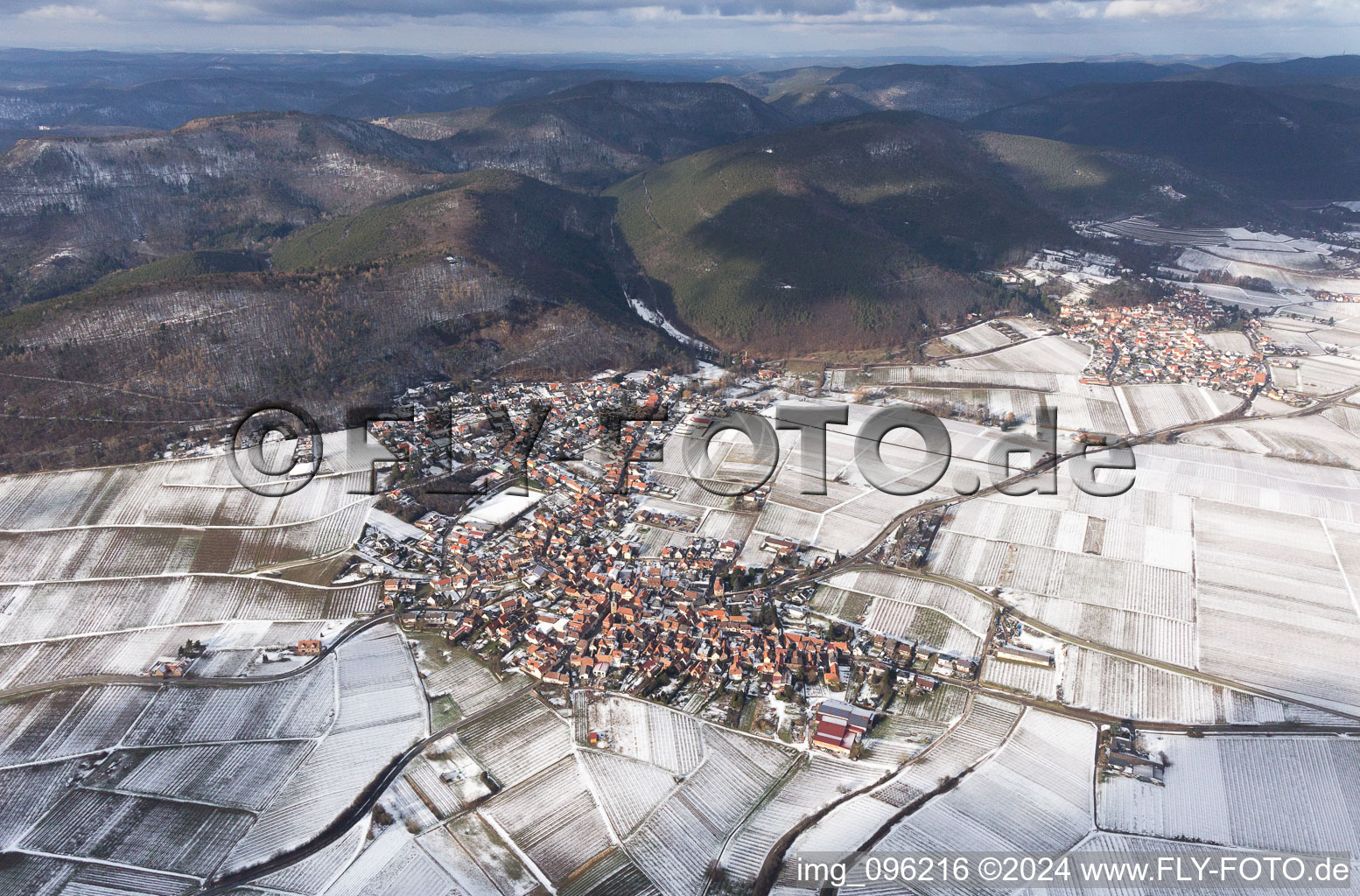 Winterlich schneebedeckte Dorf - Ansicht am Rande von Weinbergen am Haardtrand in Frankweiler im Bundesland Rheinland-Pfalz, Deutschland