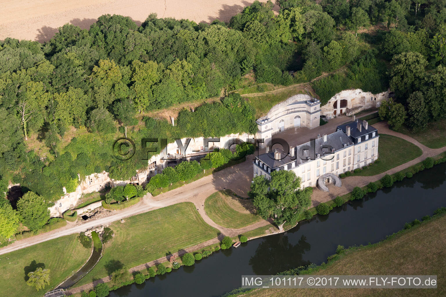 Luftaufnahme von In den Tuff des Uferhangs des Loir gegrabene Keller vor dem Schloss Château de Rochambeau in Thoré-la-Rochette in Centre-Val de Loire im Bundesland Loir-et-Cher, Frankreich