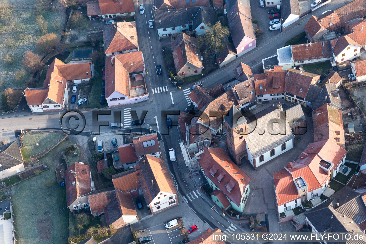 Gebäude der von einem Häuserring umgebenen lutherisch-protestantischen Wehrkirche im Dorfkern in Dossenheim-sur-Zinsel in Grand Est im Bundesland Bas-Rhin, Frankreich aus der Luft betrachtet