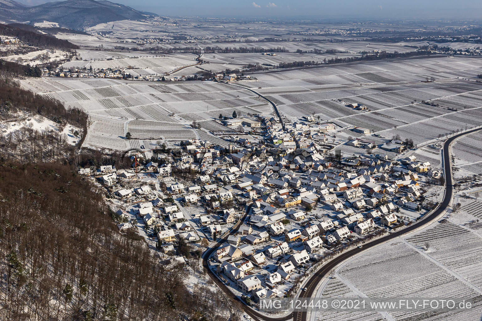 Winterlich schneebedeckte Dorf - Ansicht am Rande von Weinbergen zu Füßen des Haardtrandes des Pfälzerwalds in Eschbach im Bundesland Rheinland-Pfalz, Deutschland