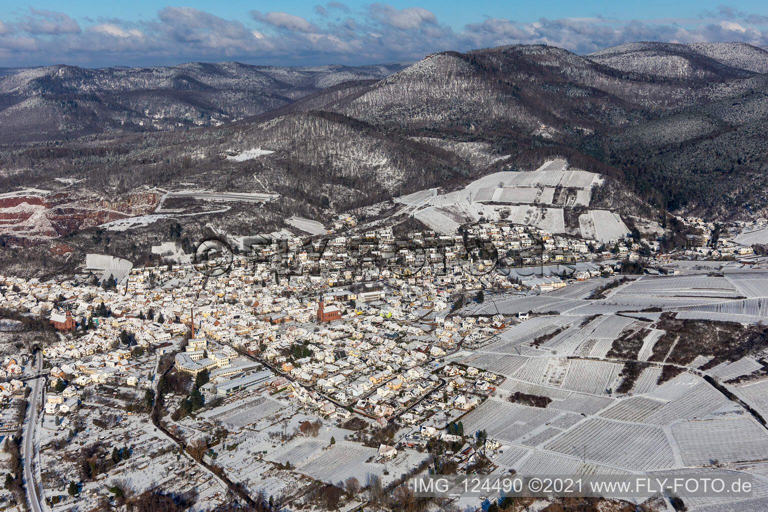 Winterlich schneebedeckte Ortsansicht der Straßen und Häuser der Wohngebiete in der von Bergen umgebenen Tallandschaft der Queich in Albersweiler im Bundesland Rheinland-Pfalz, Deutschland