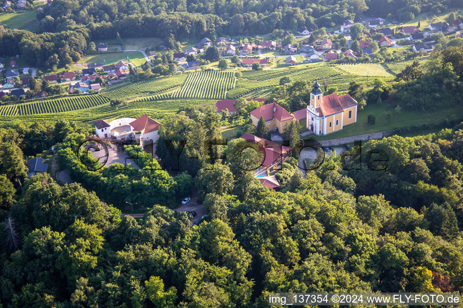 Luftaufnahme von Kirche Župnijska cerkev sv. Marije Vnebovzete und Café Huda Liza auf dem Vurberg im Ortsteil Vurberk in Duplek, Slowenien