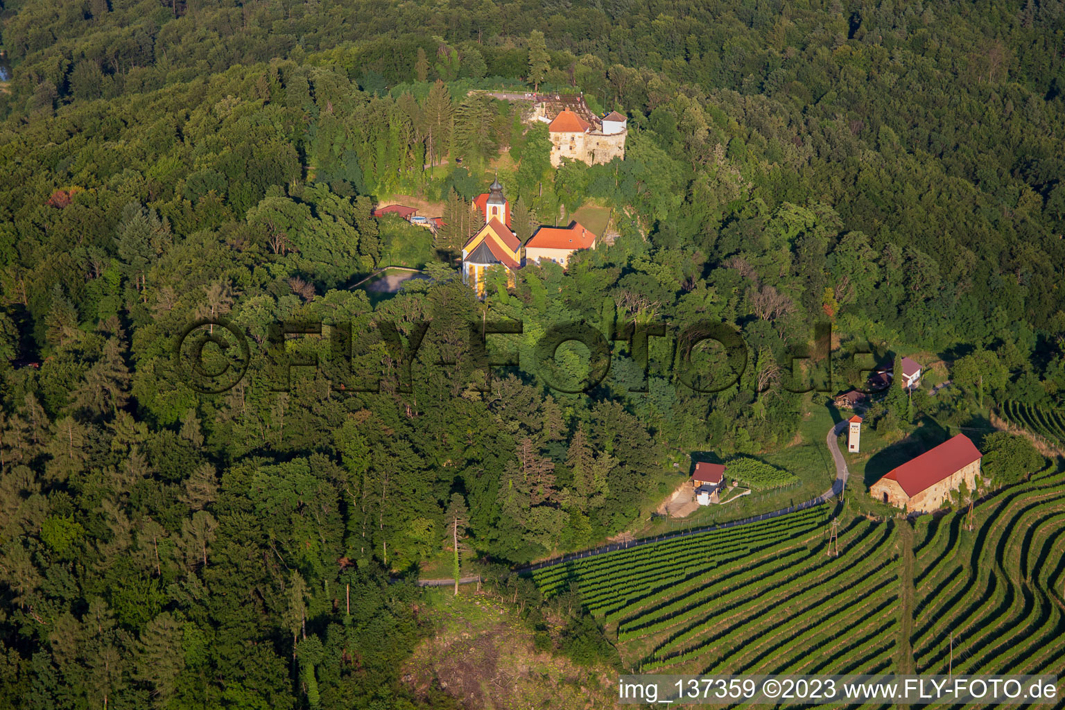 Luftaufnahme von Kirche Župnijska cerkev sv. Marije Vnebovzete und Café Huda Liza über den Weinbergen des Vurberg im Ortsteil Vurberk in Duplek, Slowenien