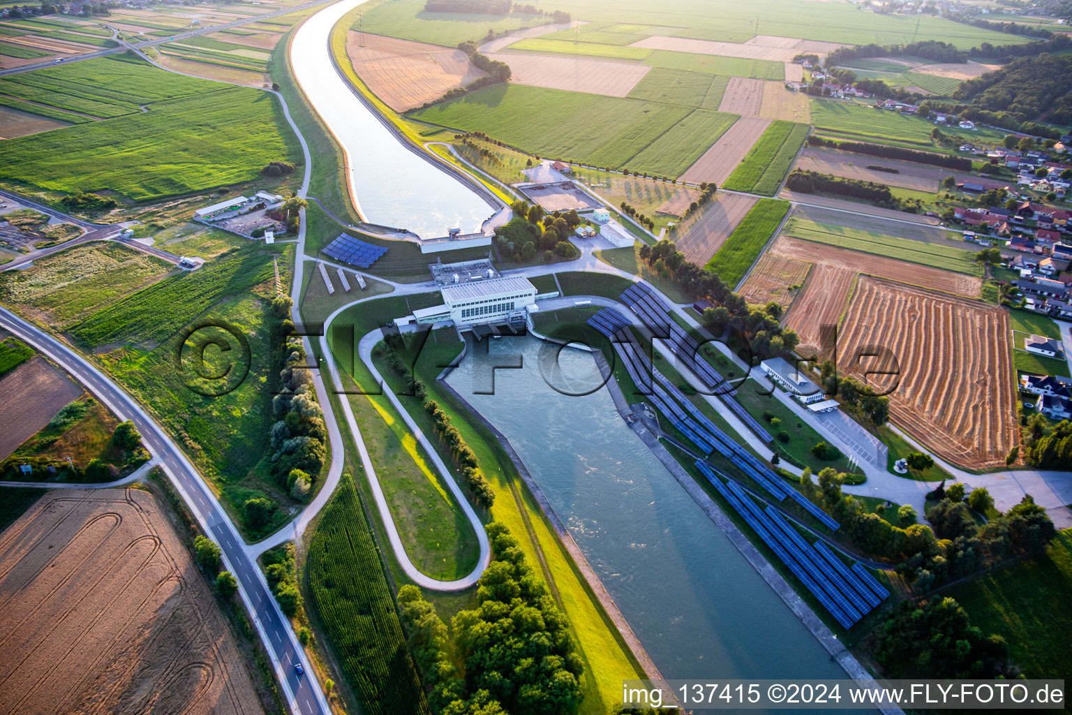 Drohnenbild von Wasserkraftwerk HE Zlatoličje mit Photovoltaik-Panels an der Uferböschung am Drau-Kanal HE Zlatoličje in Starše, Slowenien