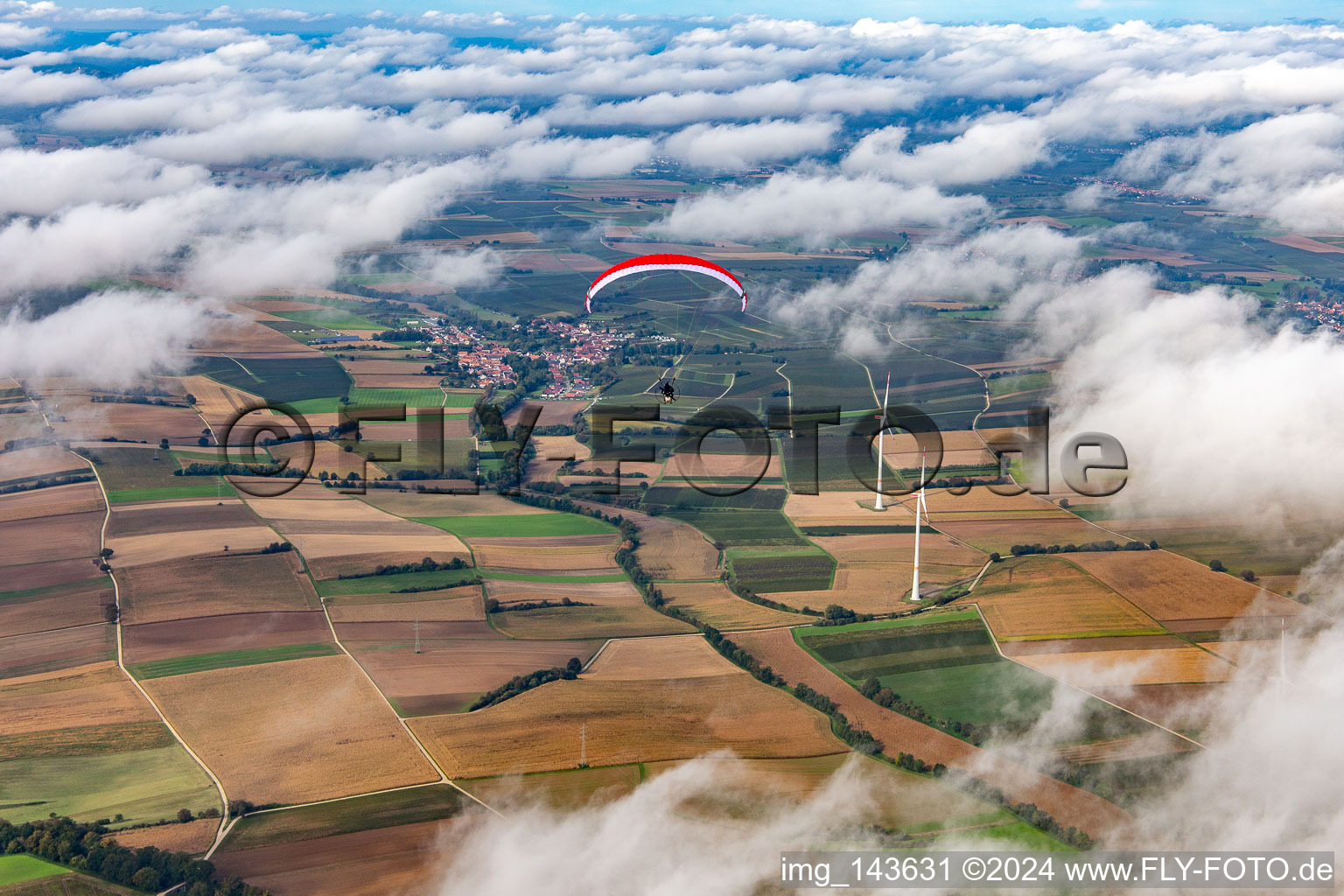 Paragleiter über dem Windpark Freckenfeld in Wolken im Bundesland Rheinland-Pfalz, Deutschland