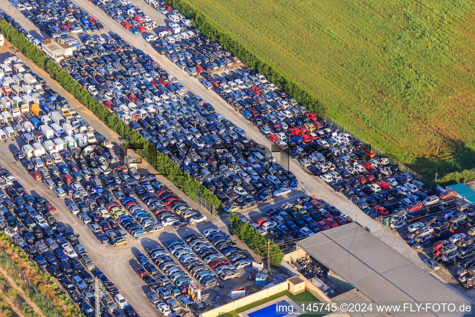 Luftbild von Reihen von gestapelten alten Fahrzeugen auf dem Schrottplatz Desguace Siglo 21 in Dos Hermanas im Bundesland Sevilla, Spanien