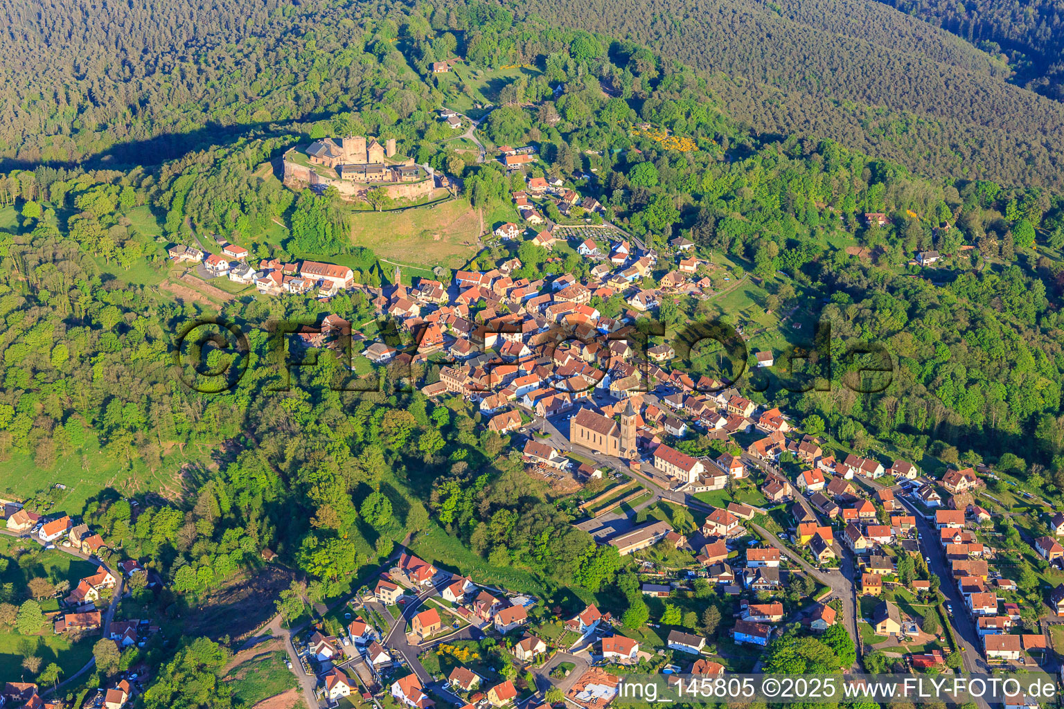 Ortsansicht in den Nordvogesen aus Nordwesten mit Kirche Notre-Dame-Marie-Auxilliatrice unter dem Château de Lichtenberg im Bundesland Bas-Rhin, Frankreich
