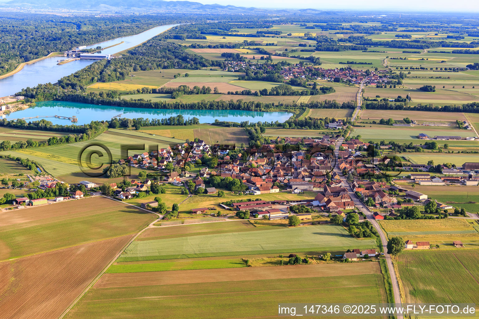 Dorfansicht aus Norden vor Baggersee/Kieswerk der Les Gravières Rhénanes SAS in Friesenheim im Bundesland Bas-Rhin, Frankreich