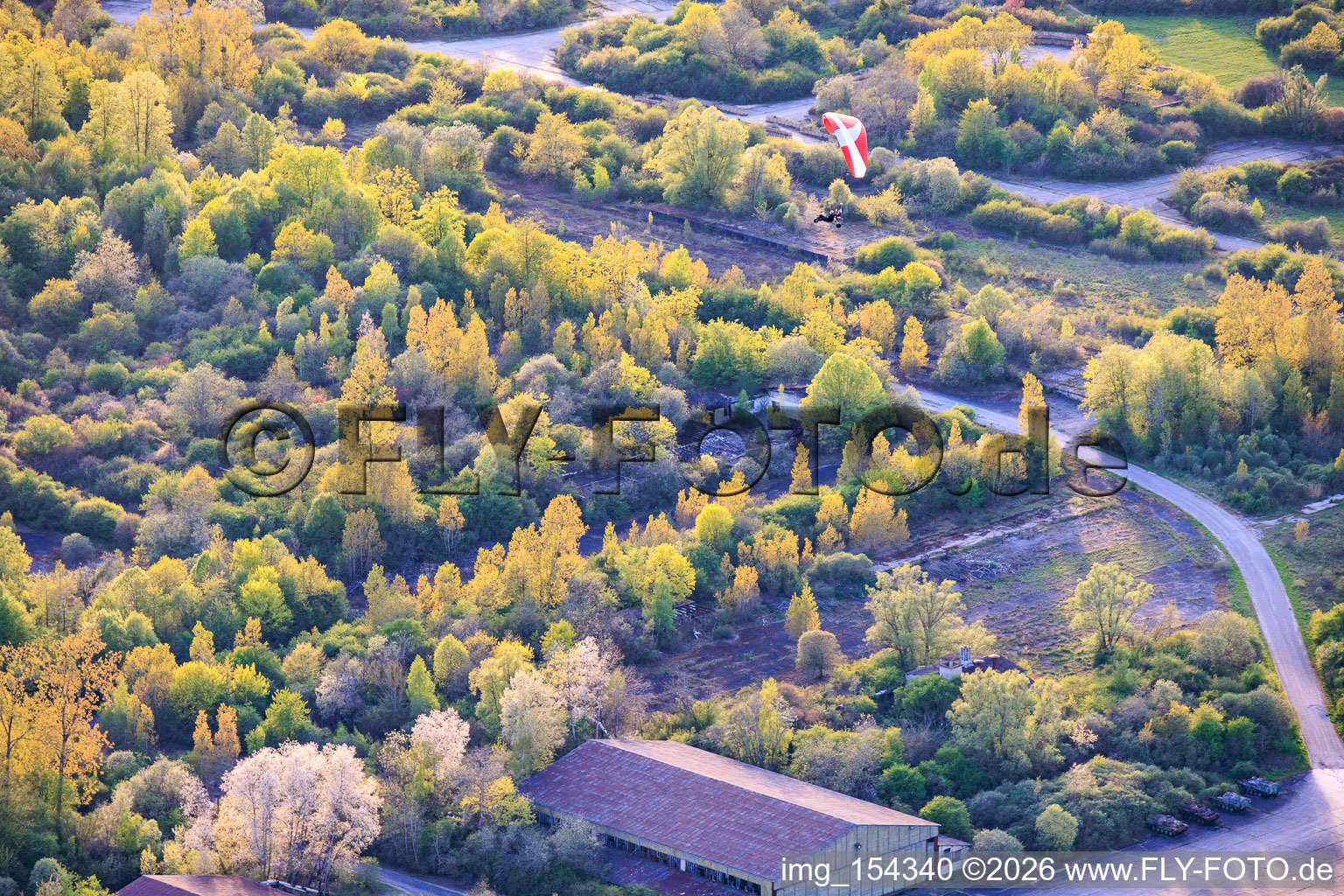 Paraglider über den Hangars am ehemaligen Miltärflugplatz Grostenquin in Bistroff im Bundesland Moselle, Frankreich