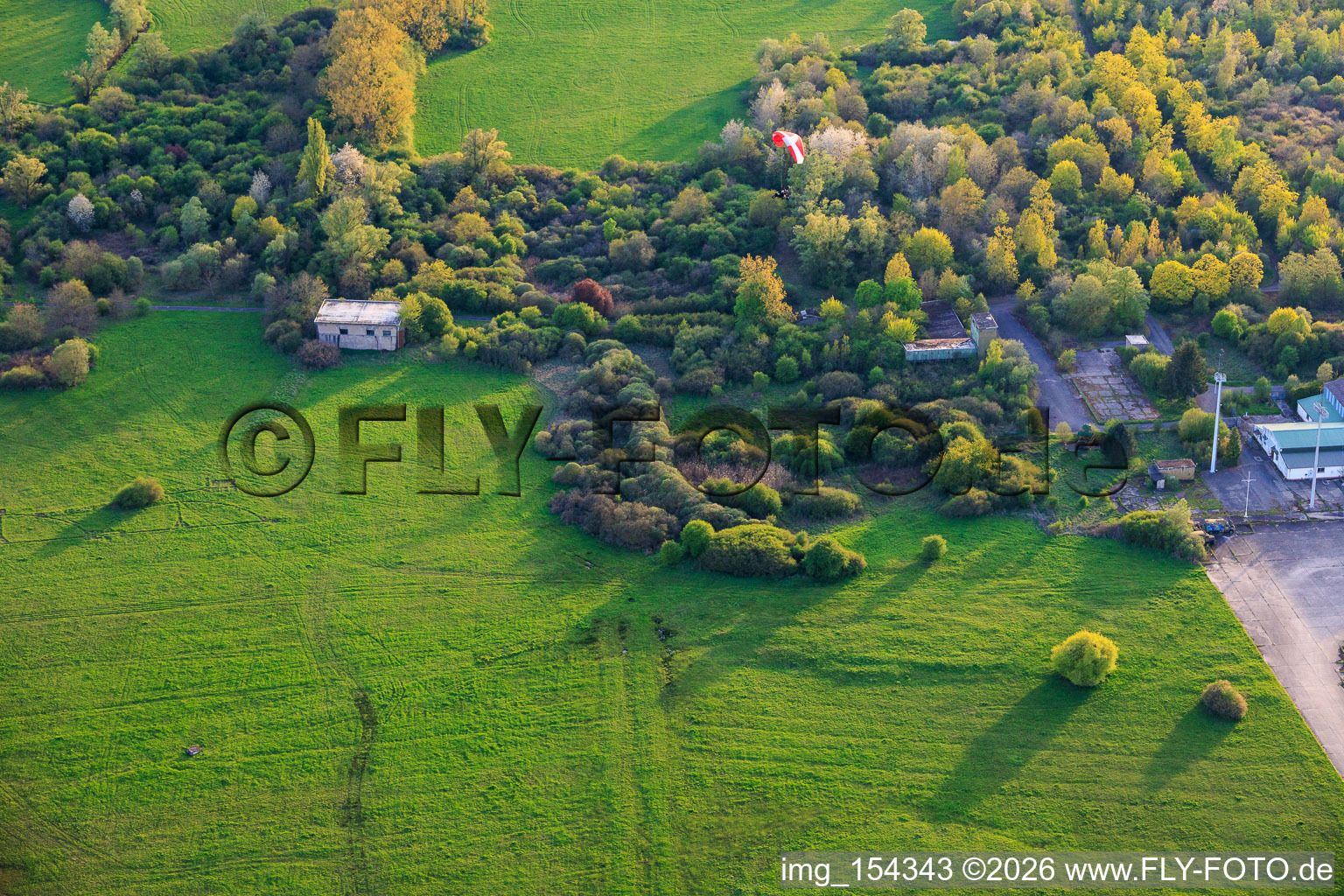 Paraglider über den Hangars am ehemaligen Miltärflugplatz Grostenquin in Bistroff im Bundesland Moselle, Frankreich