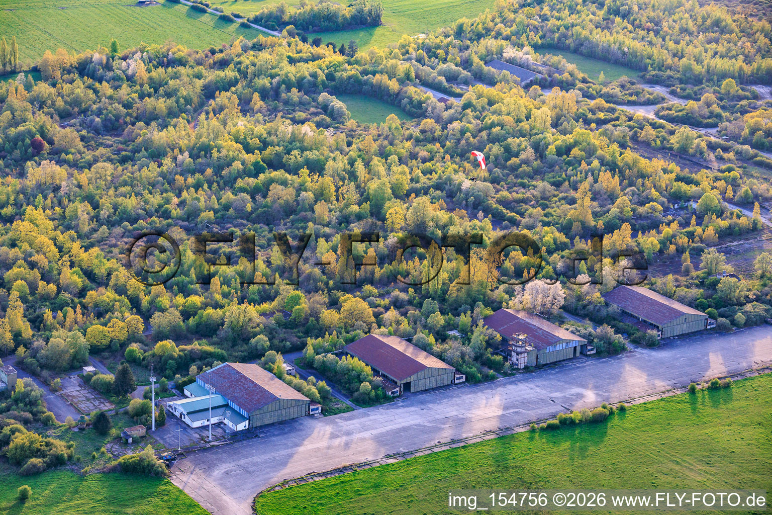 Paraglider über den Hangars am ehemaligen Miltärflugplatz Grostenquin in Bistroff im Bundesland Moselle, Frankreich