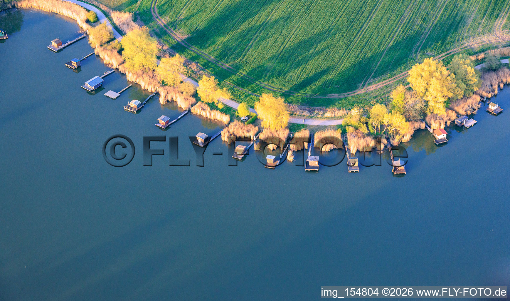 Stege mit Anglerhütten umsäumen das Ufer des Sees Etang du Welschhof in Puttelange-aux-Lacs im Bundesland Moselle, Frankreich