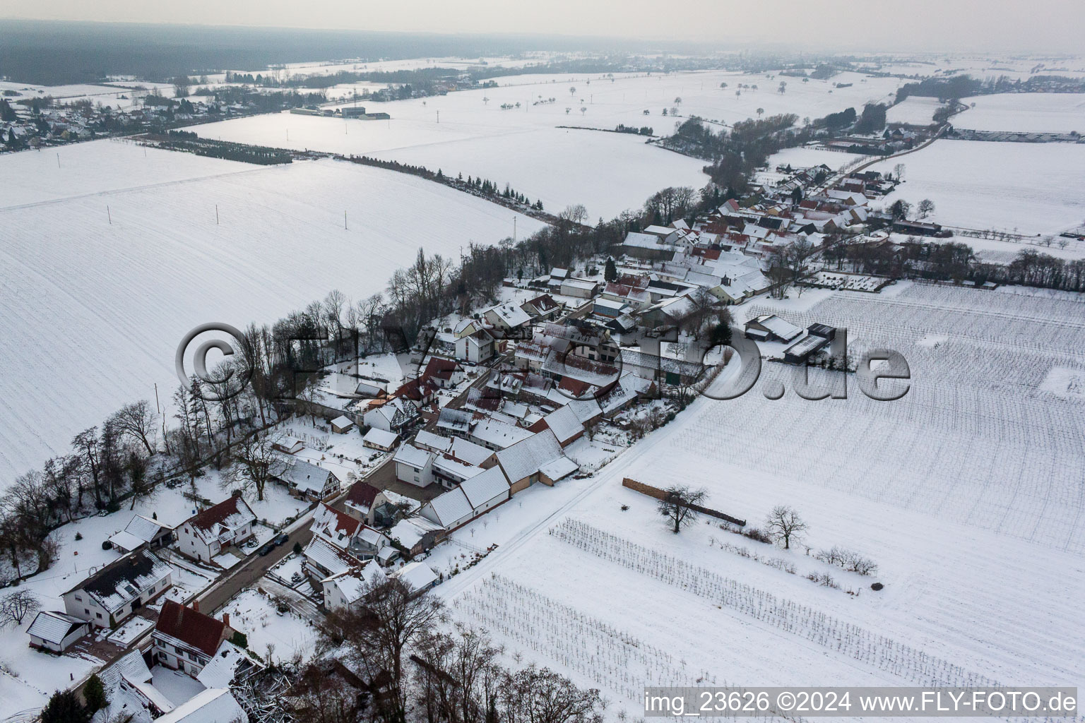 Winterlich schneebedeckte Dorf - Ansicht am Rande von landwirtschaftlichen Feldern und Nutzflächen in Vollmersweiler im Bundesland Rheinland-Pfalz, Deutschland