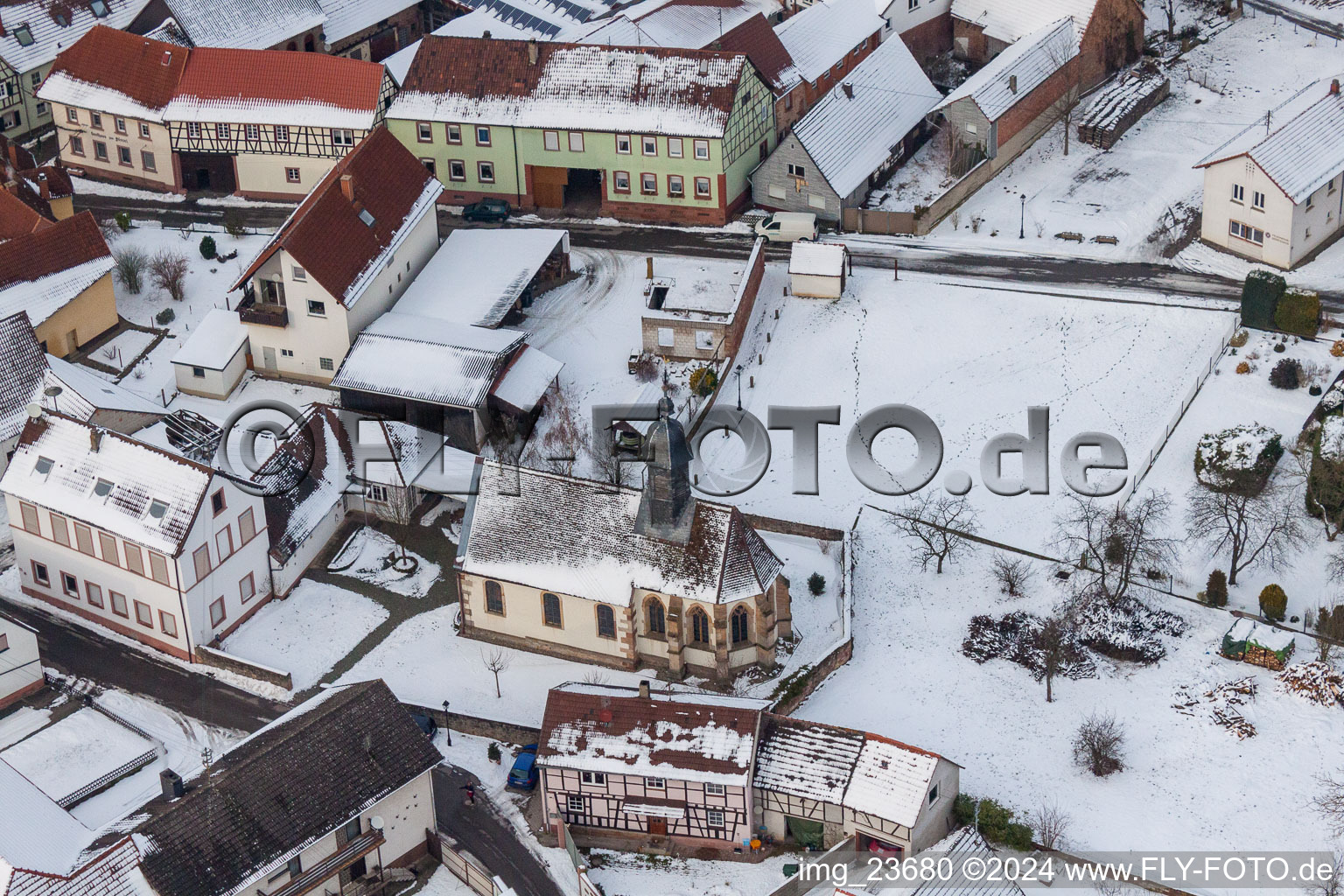 Winterlich schneebedeckte Kirchengebäude im Dorfkern in Dierbach im Bundesland Rheinland-Pfalz, Deutschland