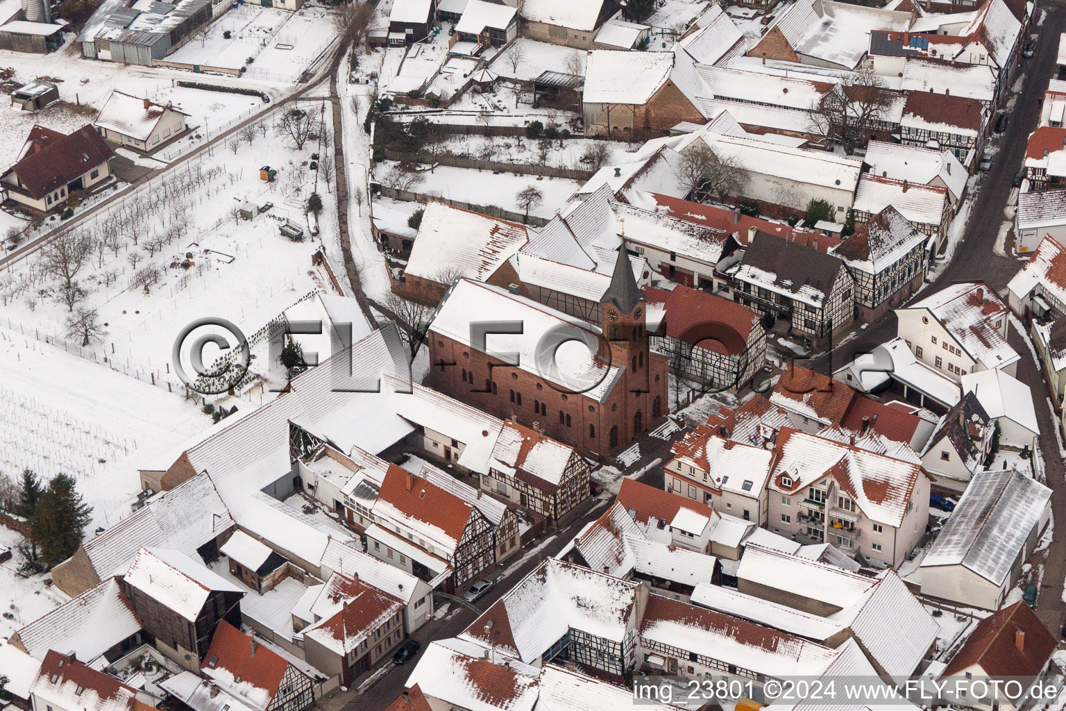 Winterlich schneebedeckte Kirchengebäude der evangelischen Kirche in der Dorfmitte in Steinweiler im Bundesland Rheinland-Pfalz, Deutschland
