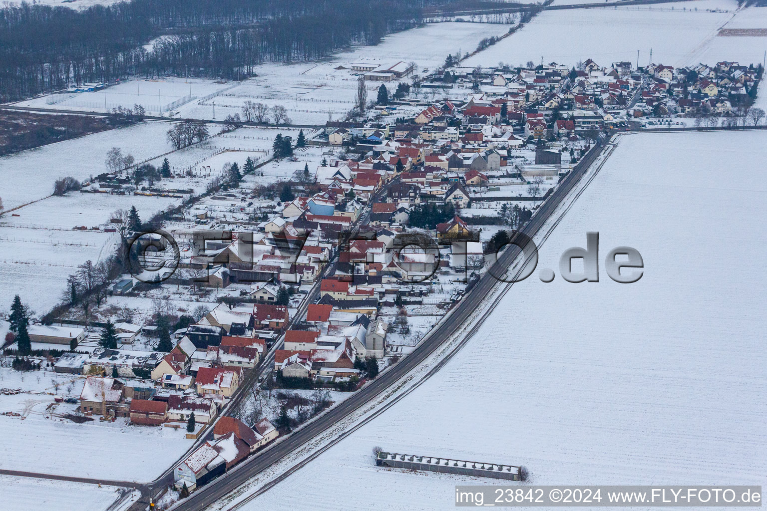 Winterlich schneebedeckte Dorf - Ansicht am Rande von landwirtschaftlichen Feldern und Nutzflächen im Ortsteil Minderslachen in Kandel im Bundesland Rheinland-Pfalz, Deutschland