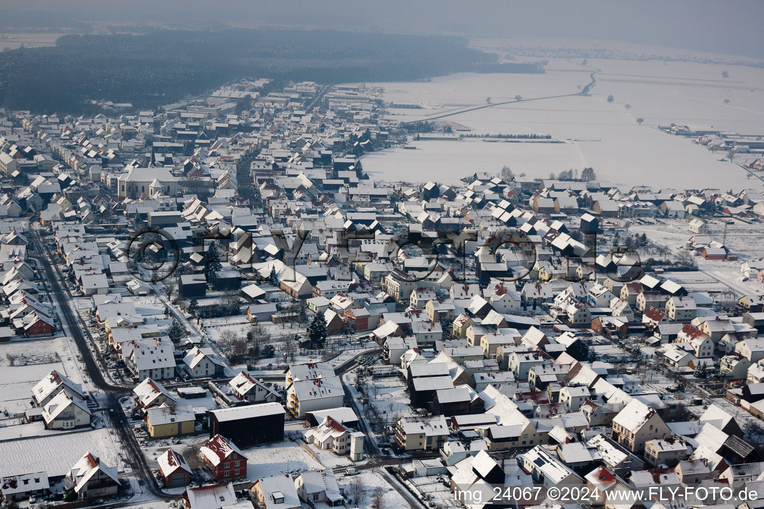 Winterlich schneebedeckte Dorf - Ansicht am Rande von landwirtschaftlichen Feldern und Nutzflächen in Hatzenbühl im Bundesland Rheinland-Pfalz, Deutschland