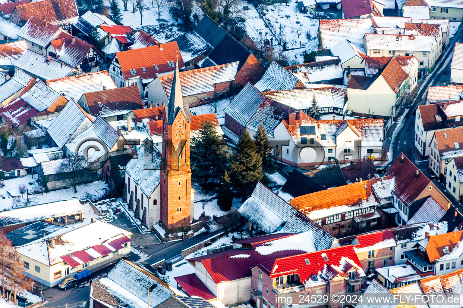 Winterlich schneebedeckte Kirchengebäude im Dorfkern in Kapellen-Drusweiler im Bundesland Rheinland-Pfalz, Deutschland