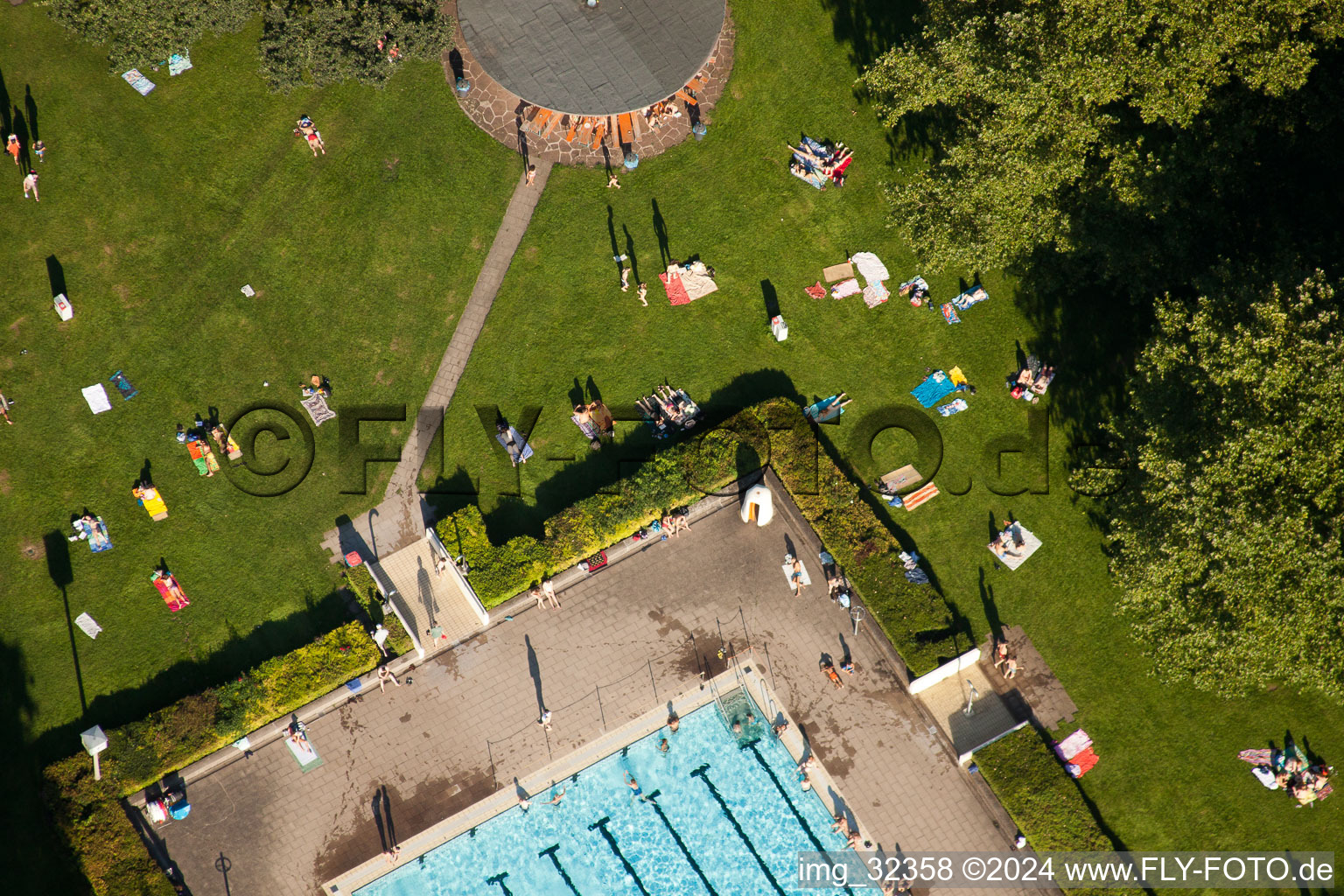 Badegäste auf den Liegewiesen am Schwimmbecken des Freibades Rüppurr in Karlsruhe im Bundesland Baden-Württemberg, Deutschland