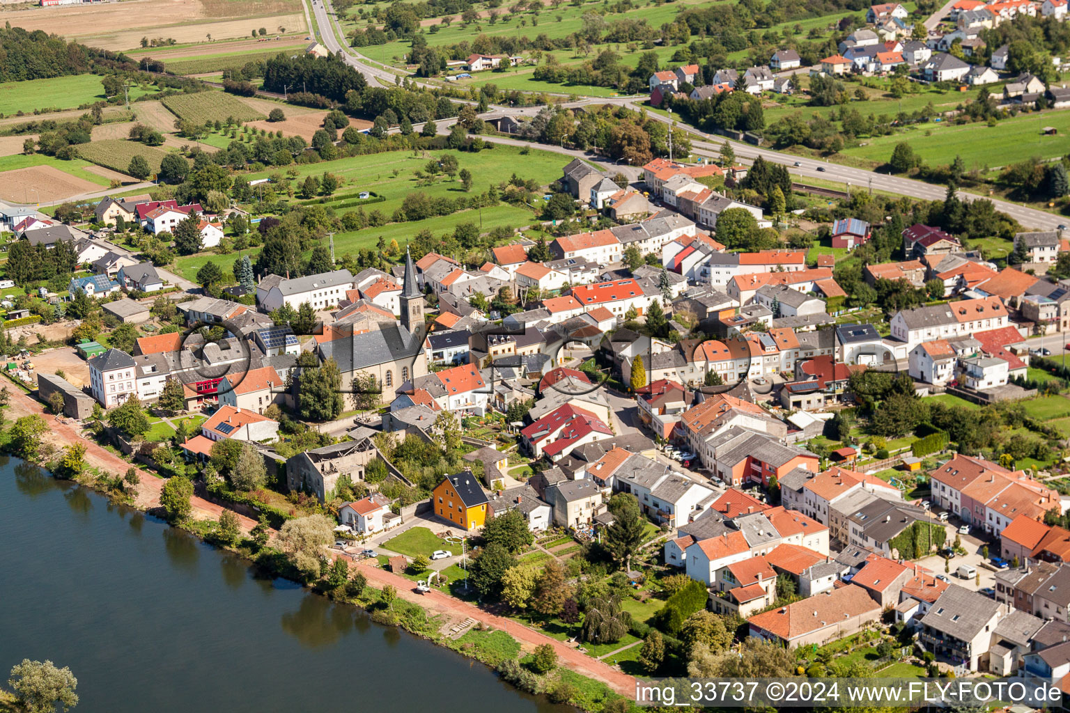 Ortschaft an den Fluss- Uferbereichen der Mosel mit St. Magaretha Kirche im Ortsteil Besch in Perl im Bundesland Saarland, Deutschland