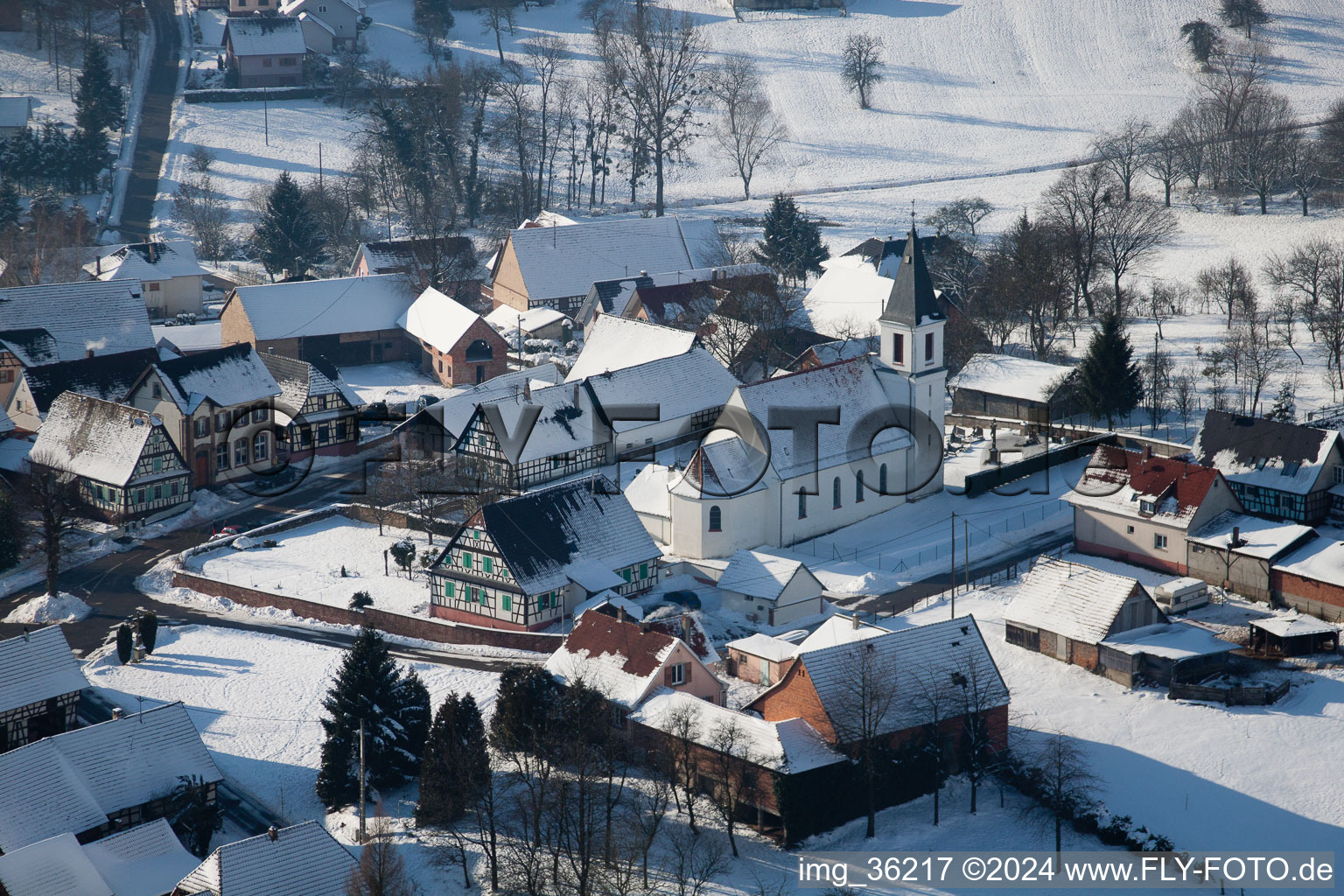 Winterlich schneebedeckte Kirchengebäude im Dorfkern in Eberbach-Seltz in Grand Est im Bundesland Bas-Rhin, Frankreich