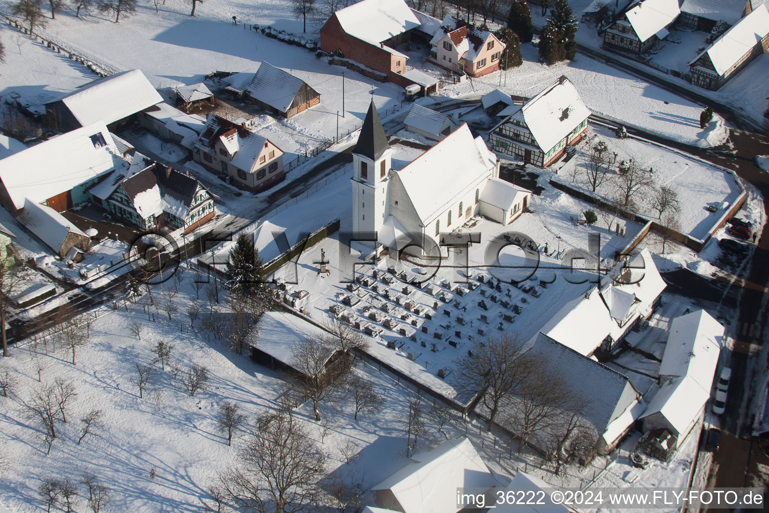 Winterlich schneebedeckte Kirchengebäude im Dorfkern in Eberbach-Seltz in Grand Est im Bundesland Bas-Rhin, Frankreich von oben