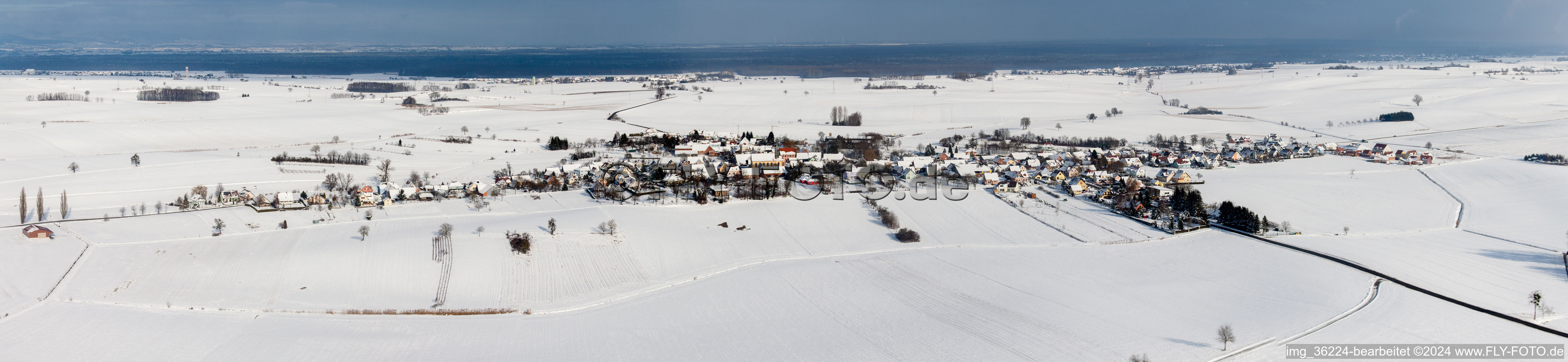 Winterlich schneebedeckte Panorama Perspektive Dorf - Ansicht am Rande von landwirtschaftlichen Feldern und Nutzflächen in Oberlauterbach in Grand Est im Bundesland Bas-Rhin, Frankreich