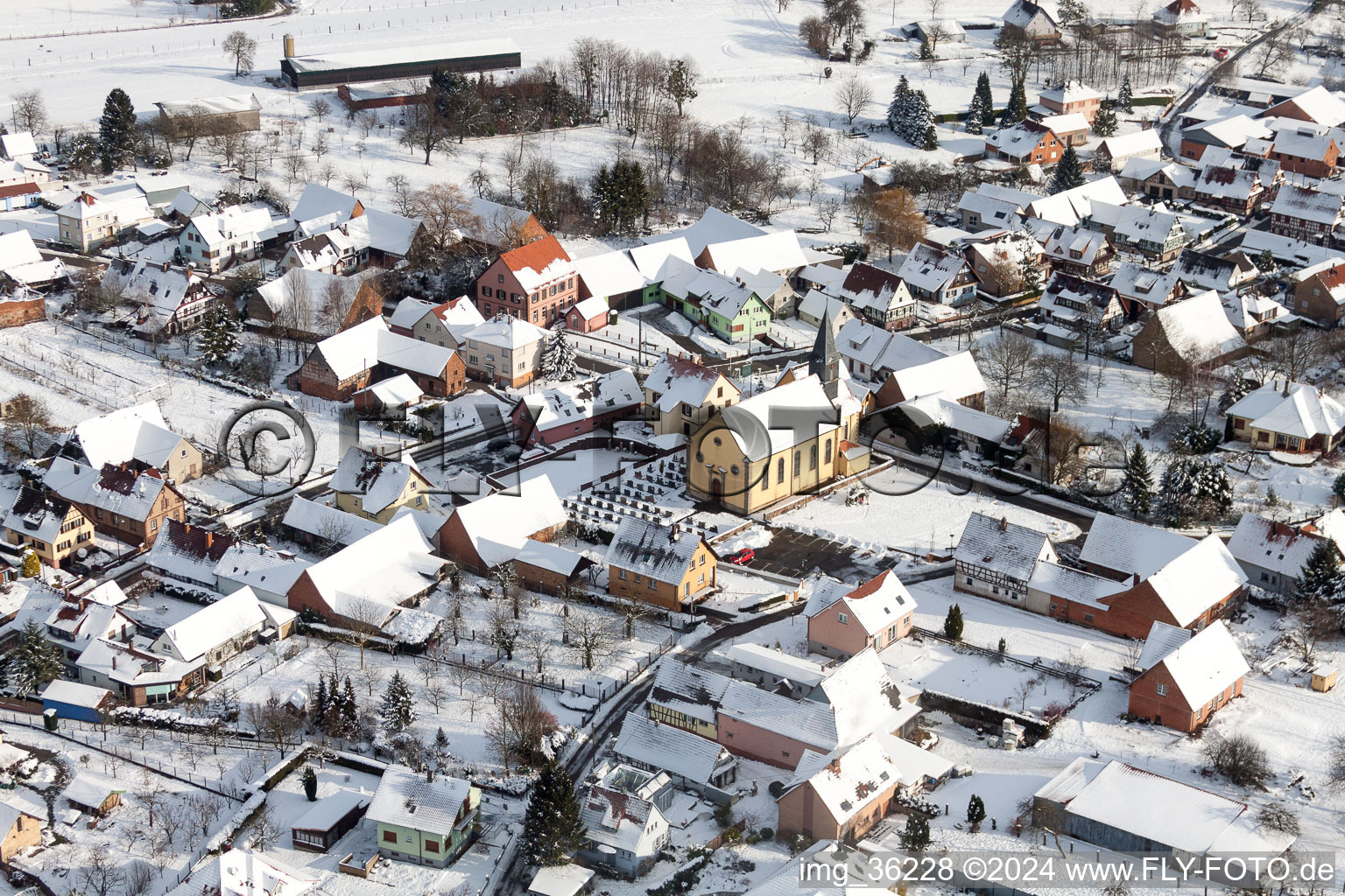 Winterlich schneebedeckte Kirchengebäude im Dorfkern in Oberlauterbach in Grand Est im Bundesland Bas-Rhin, Frankreich