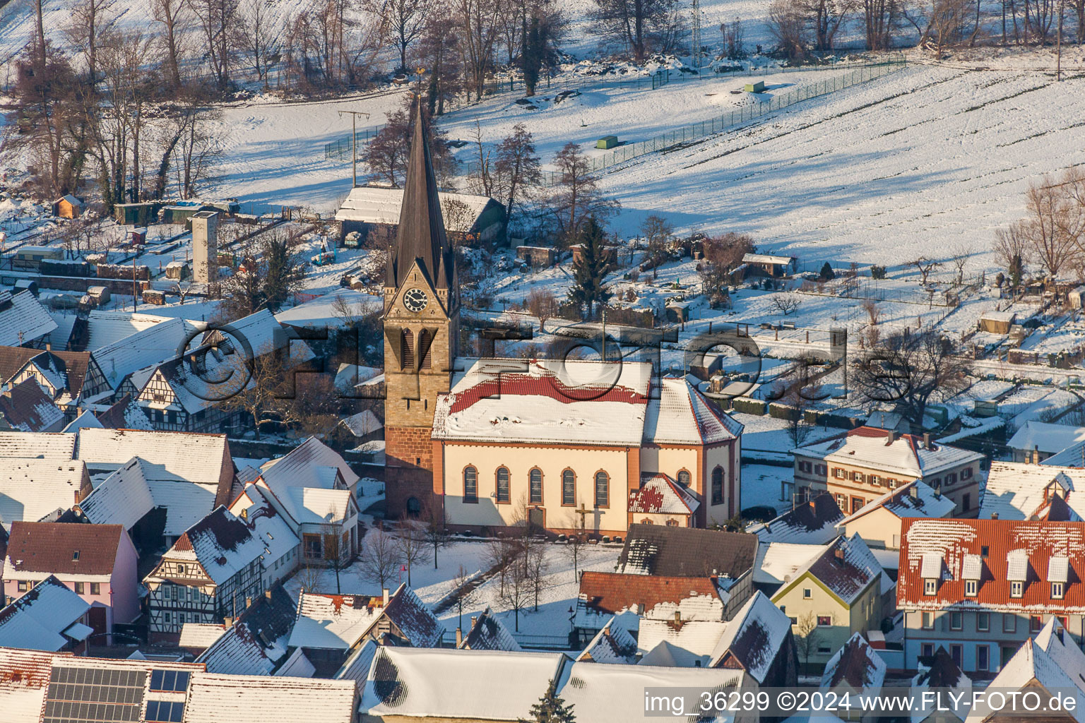 Luftaufnahme von Winterlich schneebedeckte Kirchengebäude der katholischen Kirche in der Dorfmitte in Steinweiler im Bundesland Rheinland-Pfalz, Deutschland