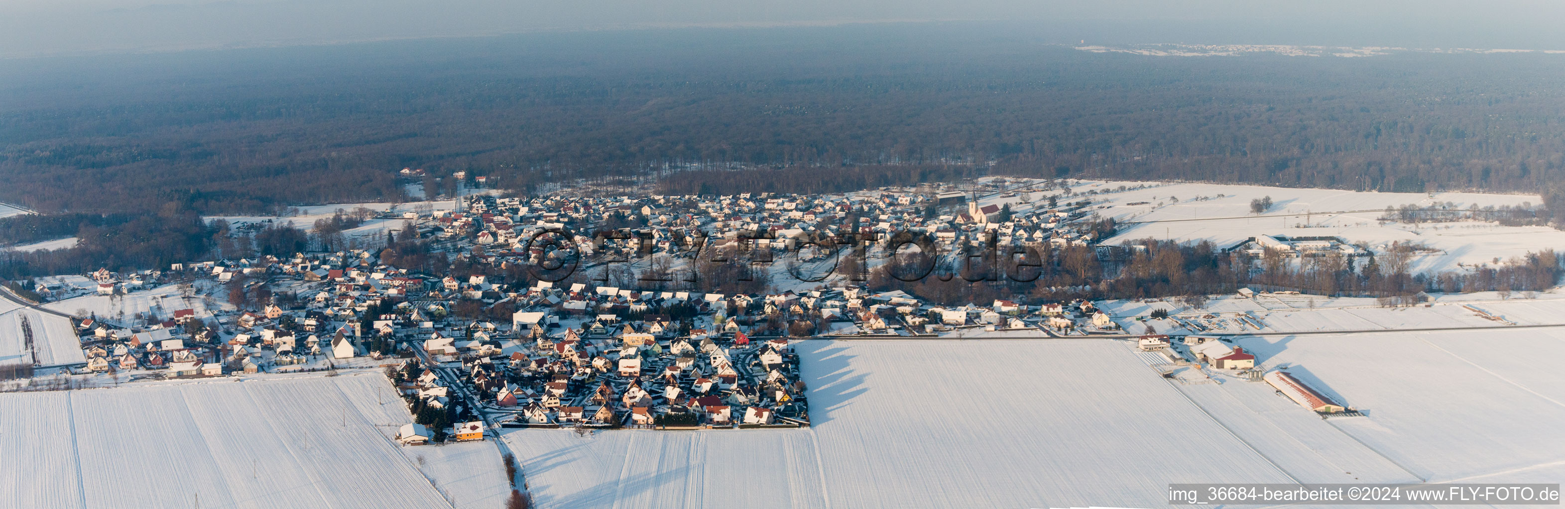 Panorama der winterlich schneebedeckten Dorf - Ansicht am Rande von landwirtschaftlichen Feldern und Nutzflächen in Scheibenhard in Grand Est im Bundesland Bas-Rhin, Frankreich
