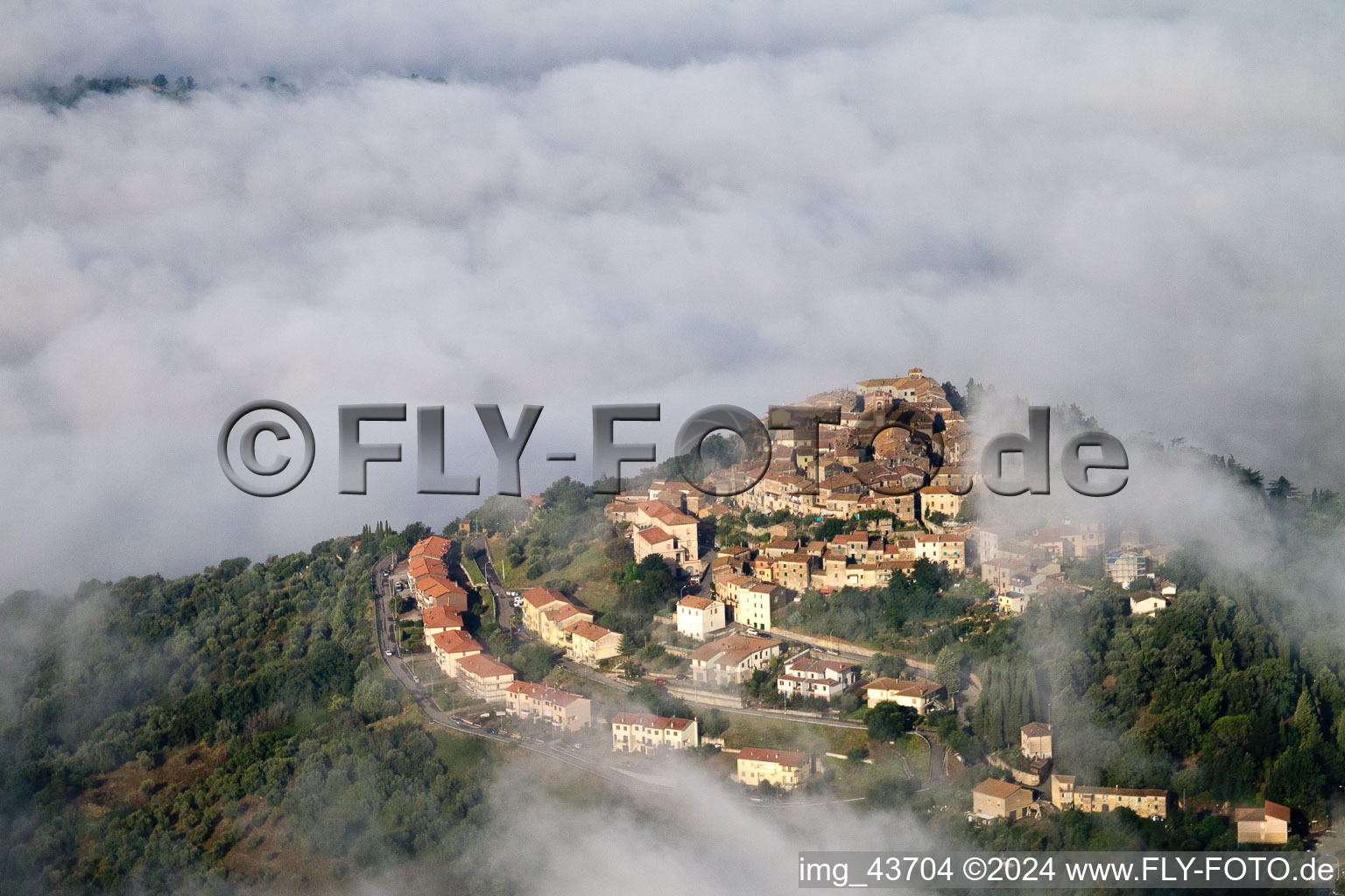 Ortsansicht mit Hochnebel- Wolken- Schicht über Straßen und Häuser der Wohngebiete in Civitella Marittima in Toscana, Italien