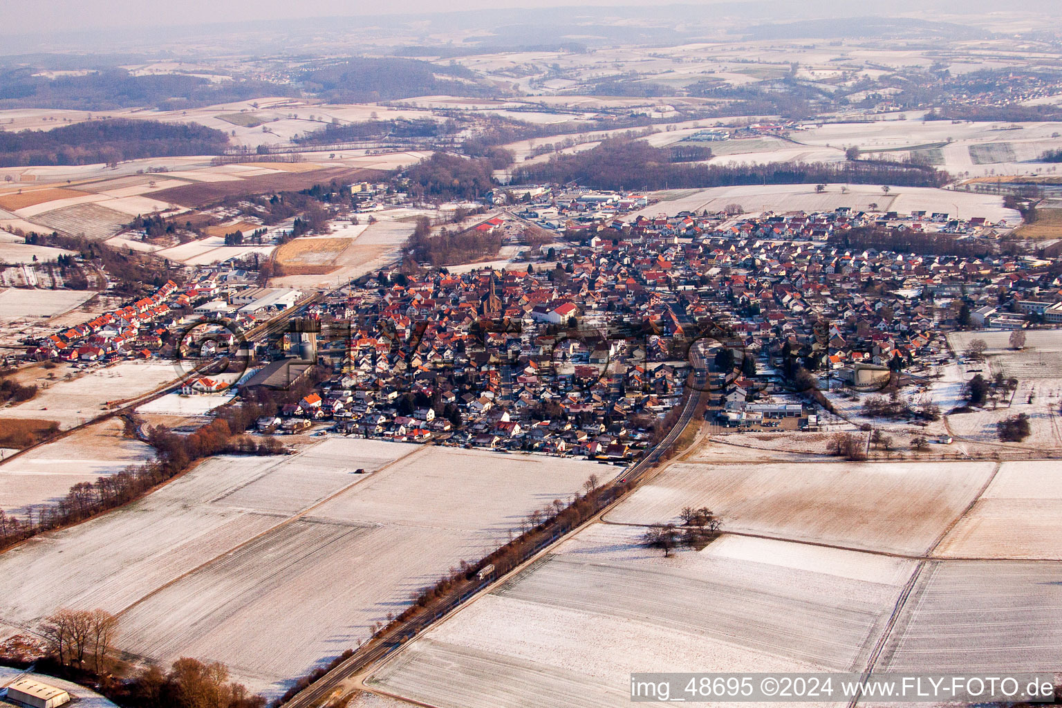 Winterlich schneebedeckte Dorf - Ansicht am Rande von landwirtschaftlichen Feldern und Nutzflächen im Ortsteil Münzesheim in Kraichtal im Bundesland Baden-Württemberg, Deutschland