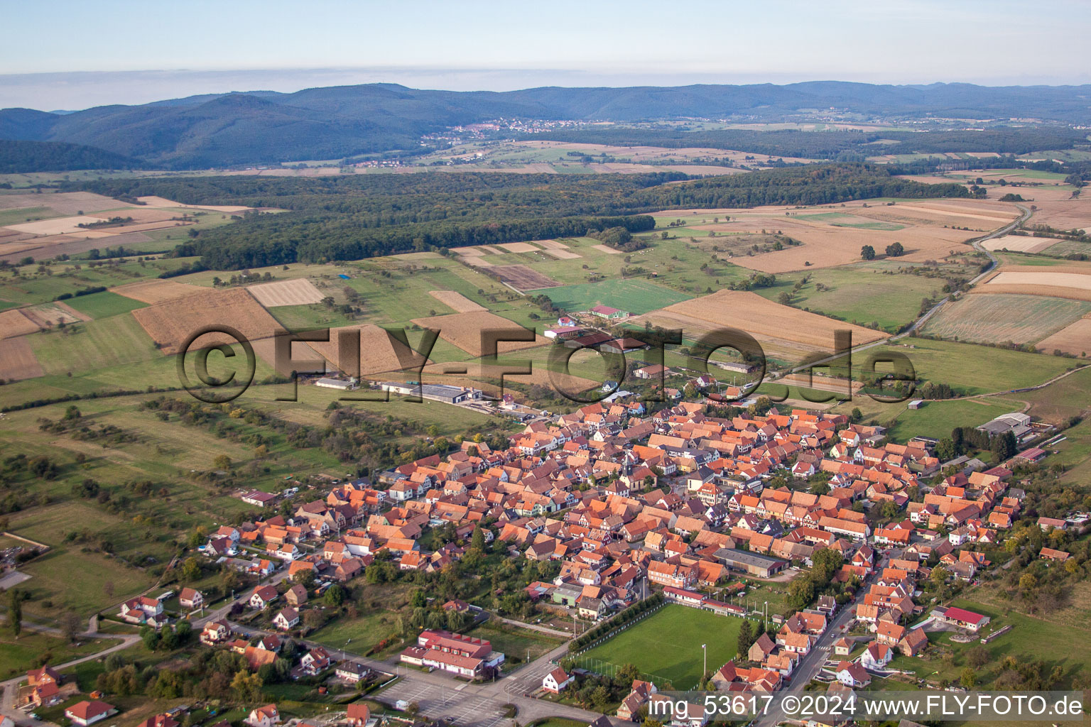 Schrägluftbild von Dorf - Ansicht am Rande von landwirtschaftlichen Feldern und Nutzflächen in Uhrwiller in Grand Est im Bundesland Bas-Rhin, Frankreich