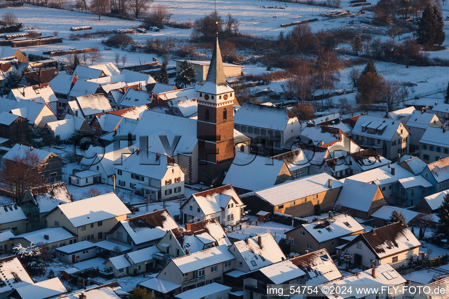 Winterlich schneebedeckte Kirchengebäude im Dorfkern im Ortsteil Schaidt in Wörth am Rhein im Bundesland Rheinland-Pfalz, Deutschland