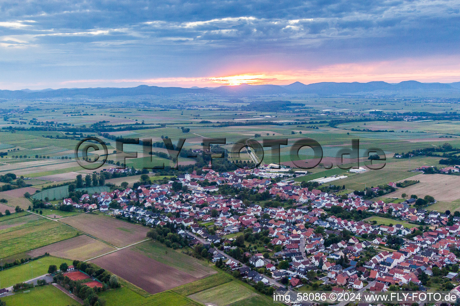 Dorf - Ansicht bei Sonnenuntergang am Rande von Feldern in Minfeld im Bundesland Rheinland-Pfalz, Deutschland