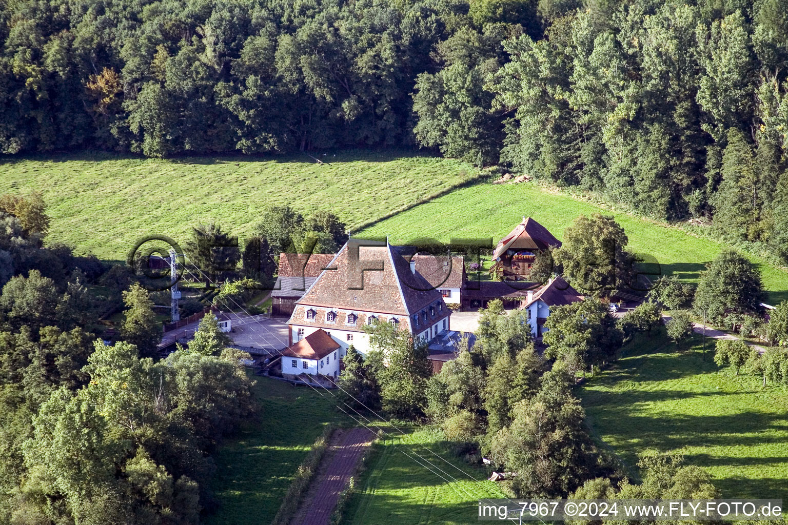 Historische Wassermühle am Gehöft eines Bauernhofes am Rand von bestellten Feldern im Ortsteil Bienwaldmühle in Scheibenhardt im Bundesland Rheinland-Pfalz, Deutschland