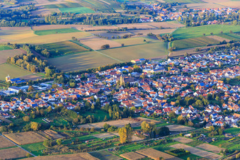 Dorfansicht zwischen herbstlichen Feldern und Wiesen mit Pfarrkirche St. Ulrich von Südwesten in Kapsweyer im Bundesland Rheinland-Pfalz, Deutschland