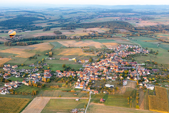 Landwirtschaftliche Nutzflächen und Feldgrenzen umsäumen das Siedlungsgebiet des Dorfes mit Heissluftballon in Kindwiller in Grand Est im Bundesland Bas-Rhin, Frankreich