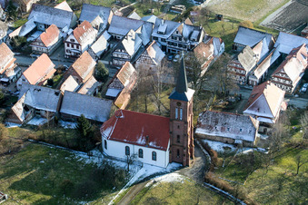 Winterlich schneebedeckte Kirchengebäude der Église Protestante de Hunspach im Dorfkern in Hunspach in Grand Est im Bundesland Bas-Rhin, Frankreich