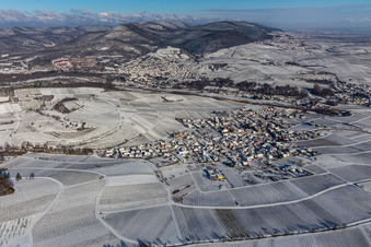 Winterlich schneebedeckte Weinberge umsäumen das Siedlungsgebiet des Dorfes in Birkweiler im Bundesland Rheinland-Pfalz, Deutschland