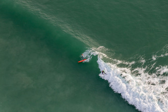 Drohnenaufname von Wellensurfer vor dem Plage de Tronoën in Saint-Jean-Trolimon im Bundesland Finistère, Frankreich