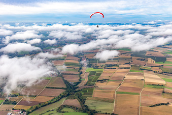Paragleiter über dem Dorf in Wolken in Vollmersweiler im Bundesland Rheinland-Pfalz, Deutschland